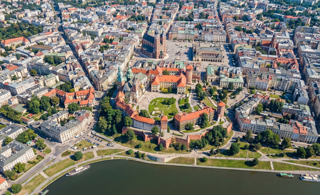 Widok z lotu ptaka na zabytkowe centrum Krakowa z Zamkiem Królewskim na Wawelu i Rynkiem Głównym, obrazujący dynamiczny rynek biznesowy, na którym prowadzona jest profesjonalna obsługa social media Kraków.